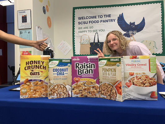 A student sitting at a table helping out at the university food pantry