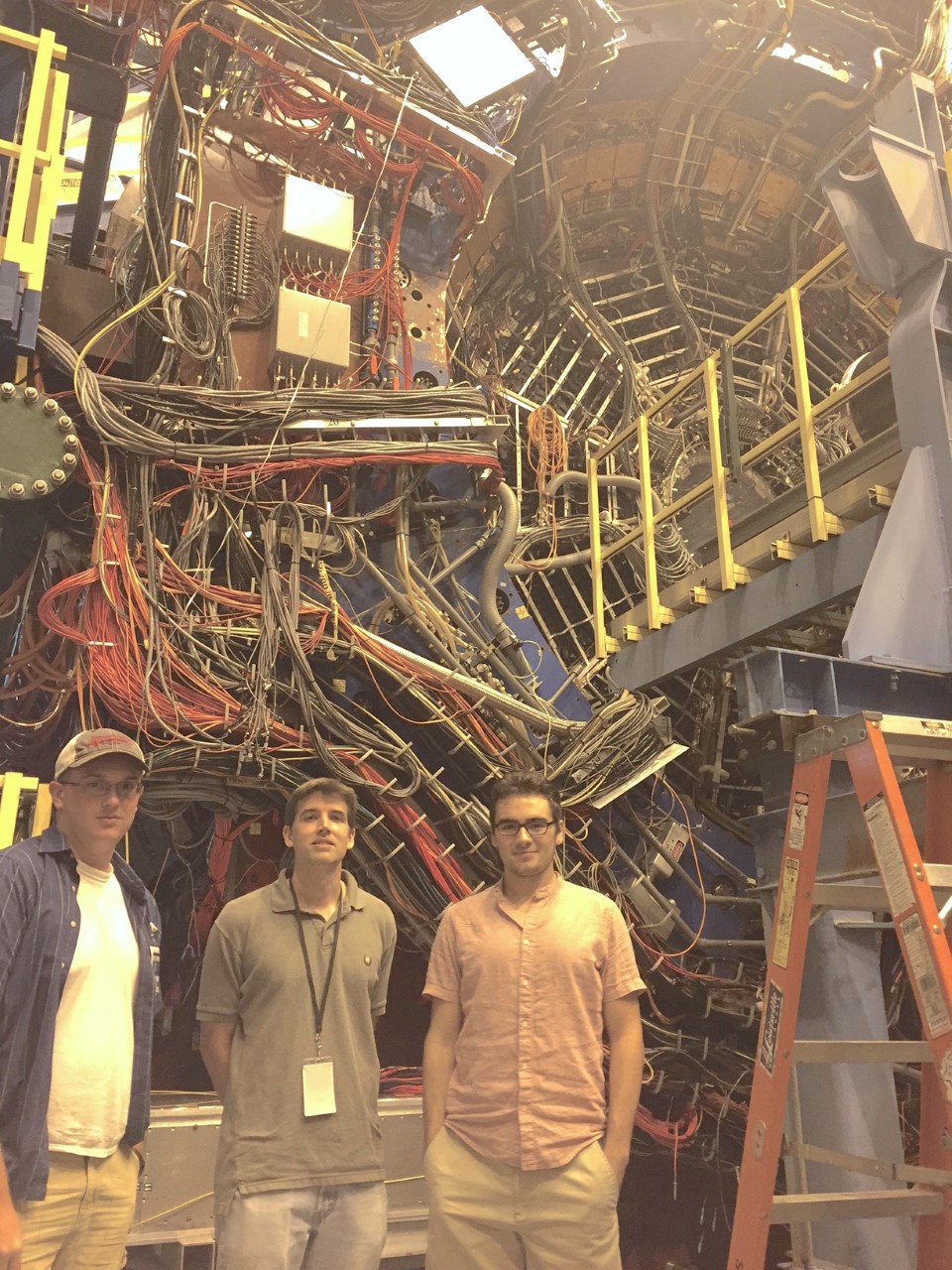 Faculty posing in from of physics equipment