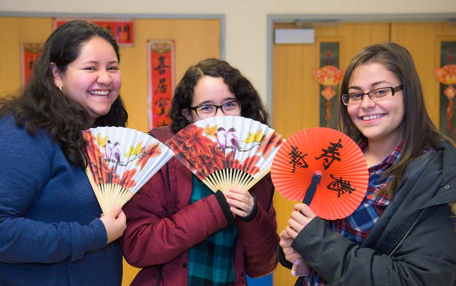 Three students holding Chinese fans