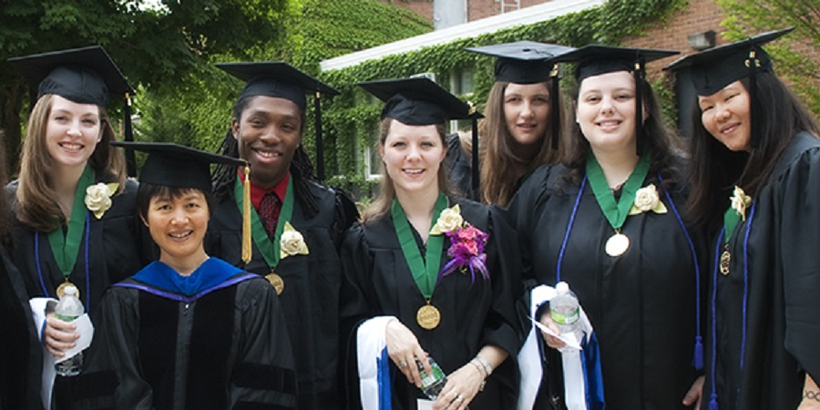 A group of students and faculty in graduation cap and gown
