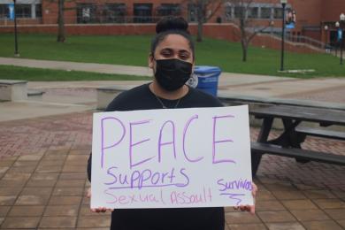 Woman holding sign saying Peace Supports Sexual Assault Survivors