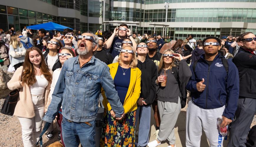 Earth Science Students in front of the SCSU Science Building looking up at the solar eclipse with sun glassesin awe.