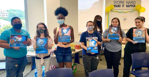 A group of students wearing face masks and holding up a pictures