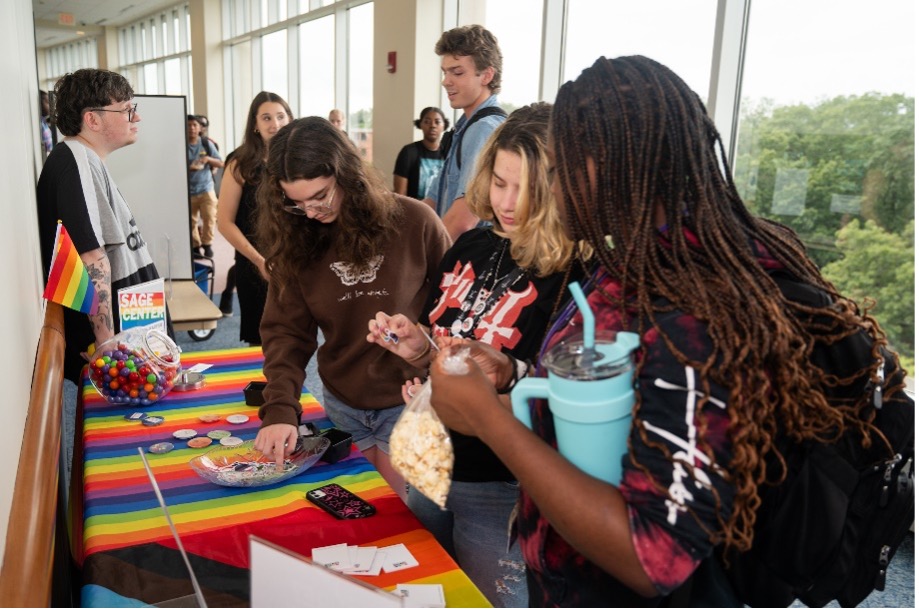 A group of students visiting a table set up by the SAGE Center. 